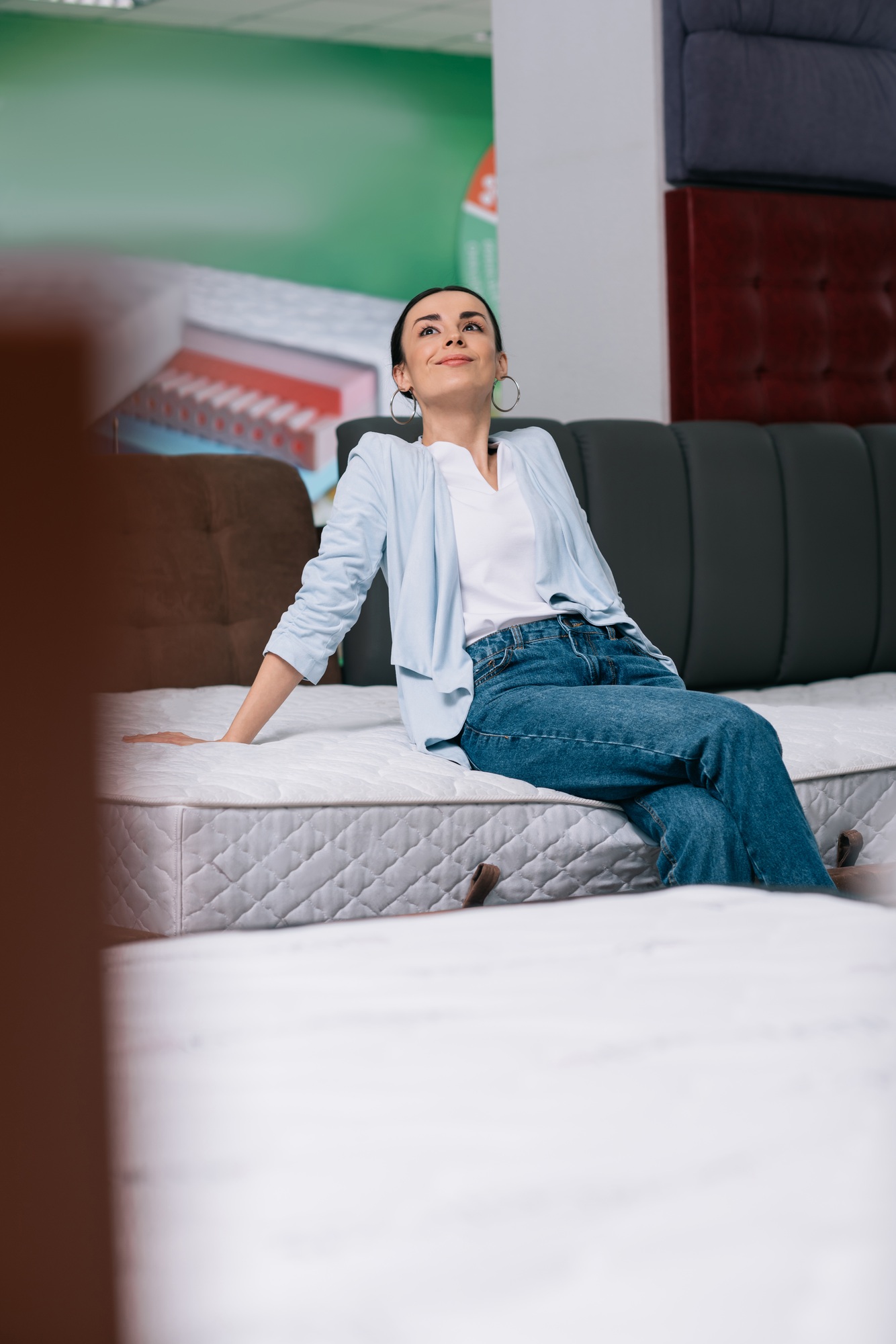 selective focus of pensive woman sitting on mattress in furniture shop