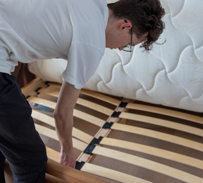 A man checks the base of the bed under the mattress in the bedroom. How to choose the right mattress