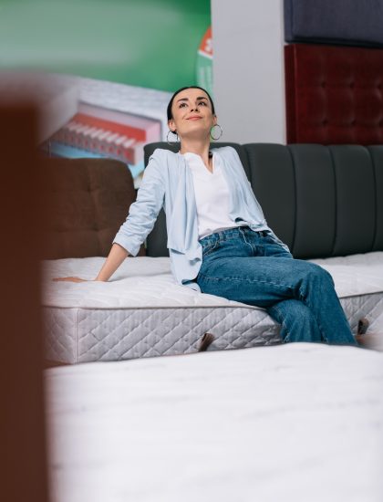 selective focus of pensive woman sitting on mattress in furniture shop